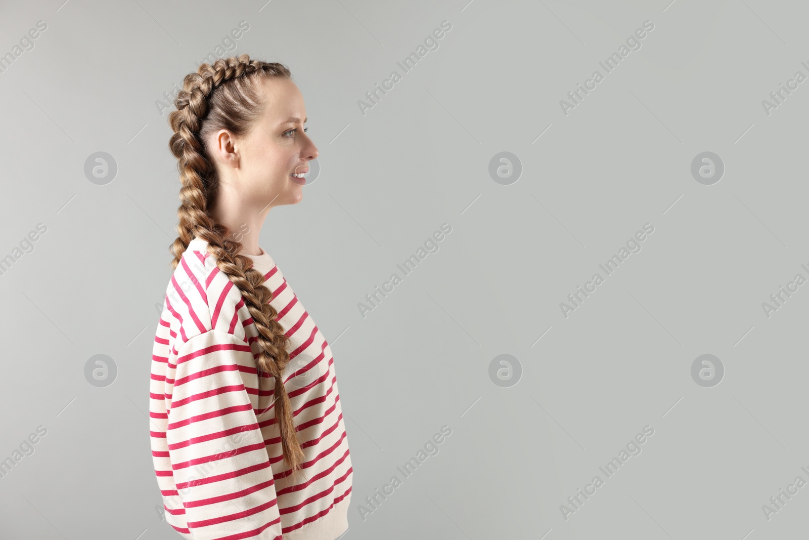 Photo of Woman with braided hair on grey background, space for text