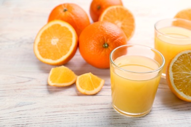 Photo of Delicious orange juice and fresh fruits on white wooden table. Space for text