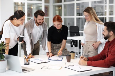 Photo of Team of employees working together in office