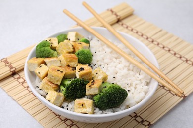 Bowl of rice with fried tofu and broccoli on white table, closeup
