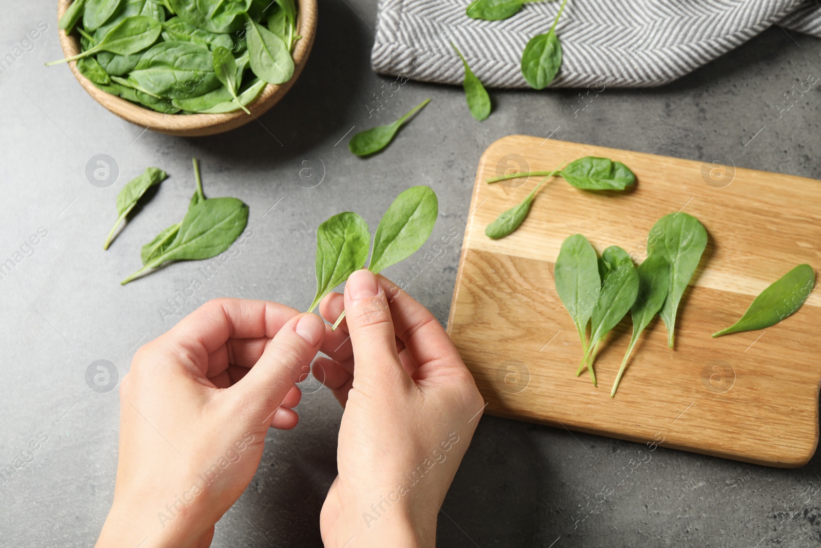 Photo of Woman with fresh green healthy spinach at grey table, top view