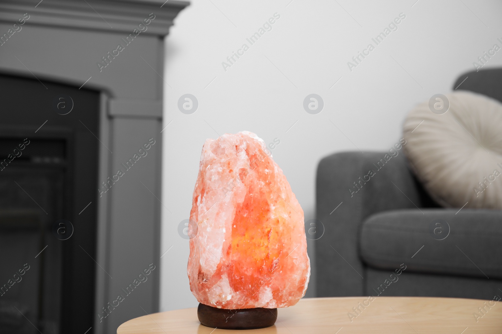 Photo of Himalayan salt lamp on wooden table in living room