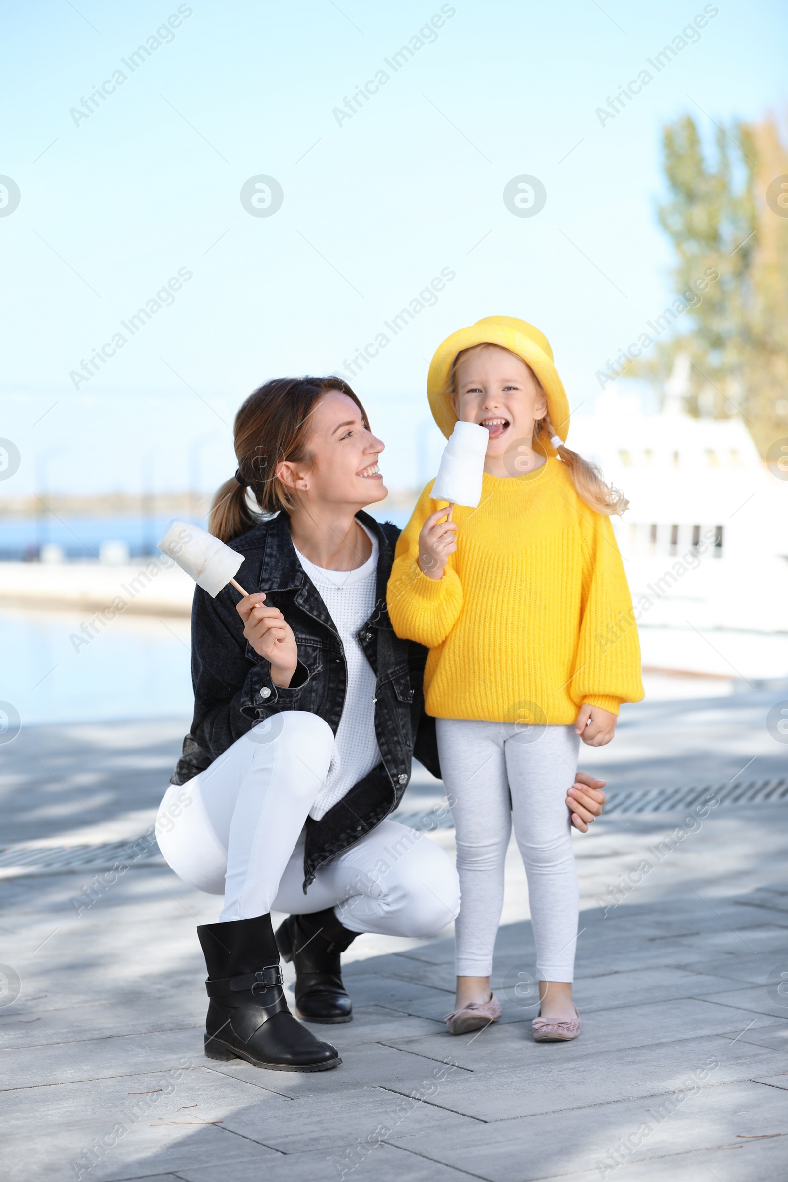 Photo of Young woman and little girl with cotton candies outdoors