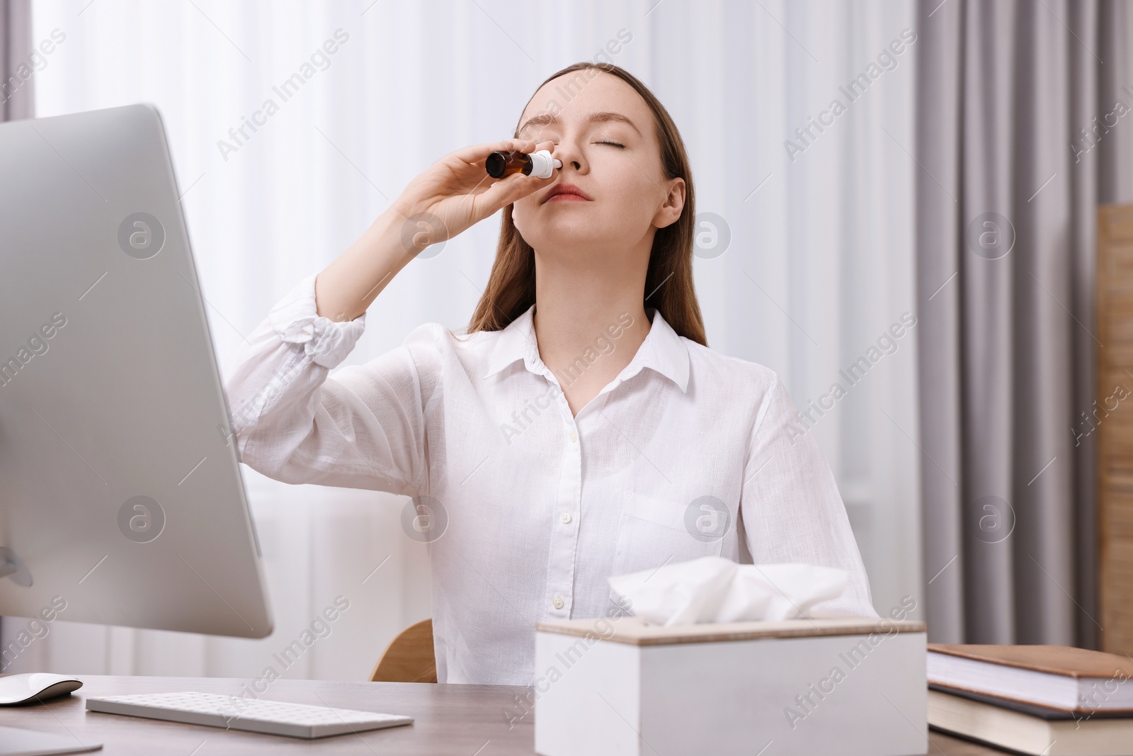 Photo of Medical drops. Young woman using nasal spray at home indoors