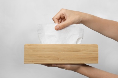 Photo of Woman taking paper tissue from holder on light background, closeup