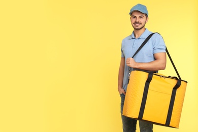 Young courier with thermo bag on color background, space for text. Food delivery service