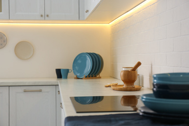 Photo of Stylish kitchen interior with modern cooktop and white furniture