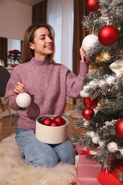 Young woman decorating Christmas tree at home