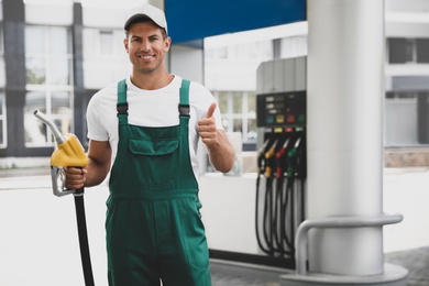 Photo of Worker with fuel pump nozzle at modern gas station