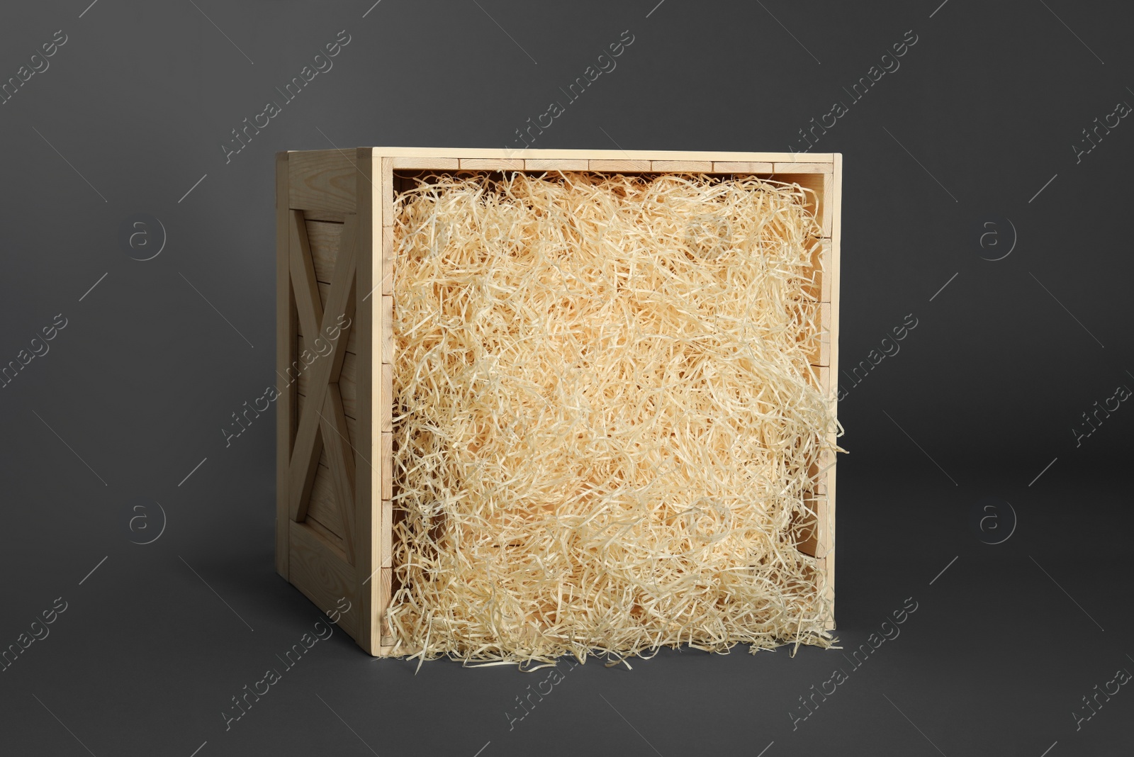 Photo of Wooden crate with shavings on dark background