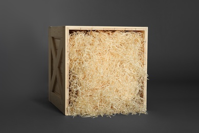 Photo of Wooden crate with shavings on dark background