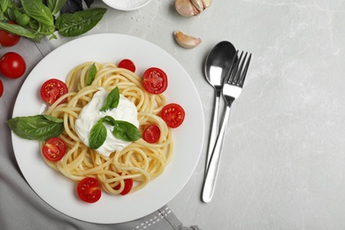 Photo of Delicious spaghetti with sour cream served on light grey marble table, flat lay. Space for text