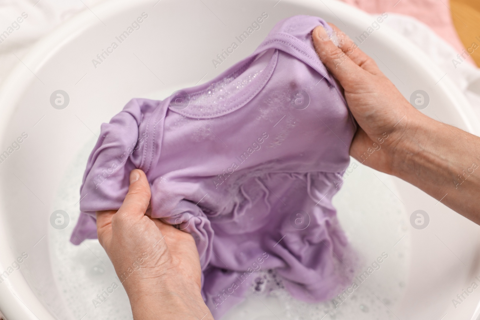 Photo of Woman washing baby clothes in basin, closeup