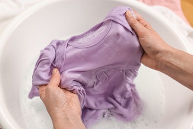 Photo of Woman washing baby clothes in basin, closeup