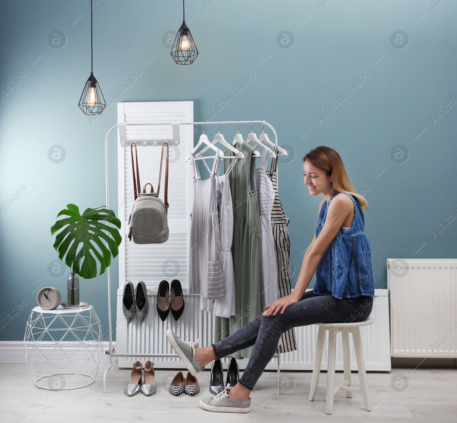 Photo of Young woman trying on shoes. Stylish dressing room interior