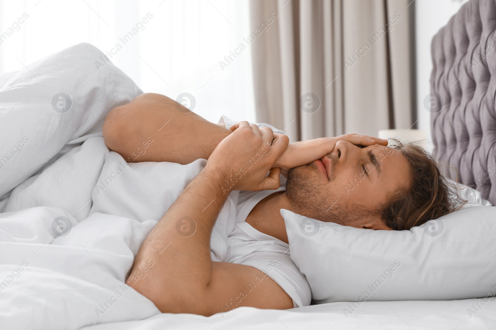 Photo of Sleepy young man lying on pillow at home. Bedtime