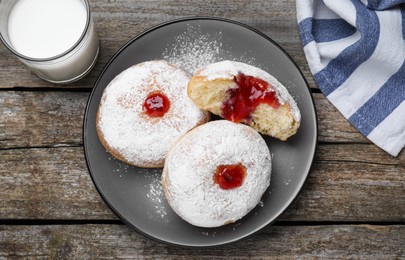 Photo of Delicious jelly donuts served with milk on wooden table, flat lay