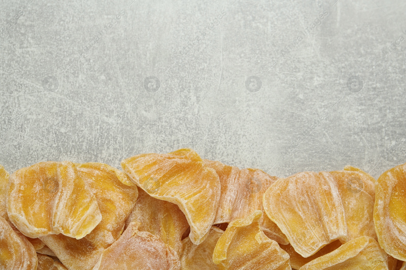 Photo of Delicious dried jackfruit slices on light grey table, flat lay. Space for text