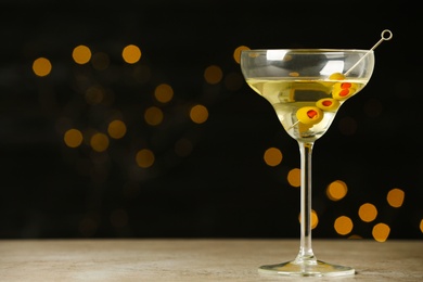 Photo of Glass of Classic Dry Martini with olives on grey table against blurred background. Space for text
