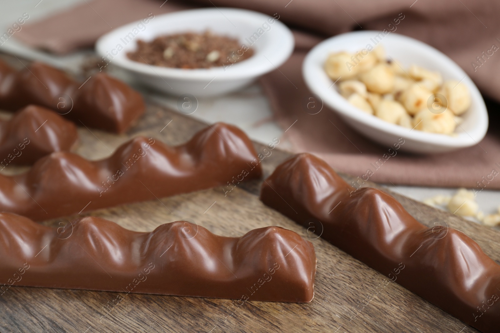 Photo of Tasty chocolate bars on wooden board, closeup. Space for text