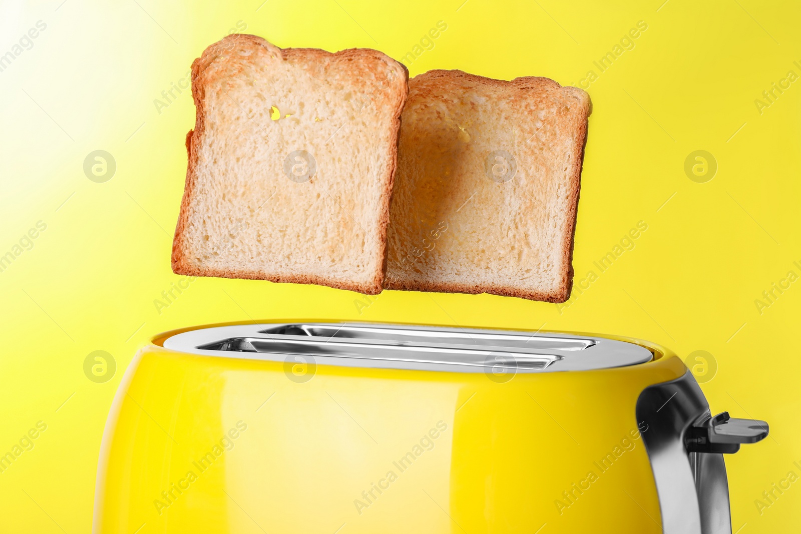 Photo of Modern toaster with roasted bread against yellow background, closeup