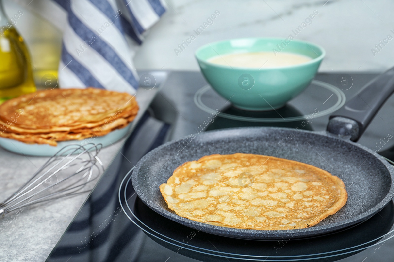 Photo of Delicious thin pancake in frying pan on induction stove, closeup