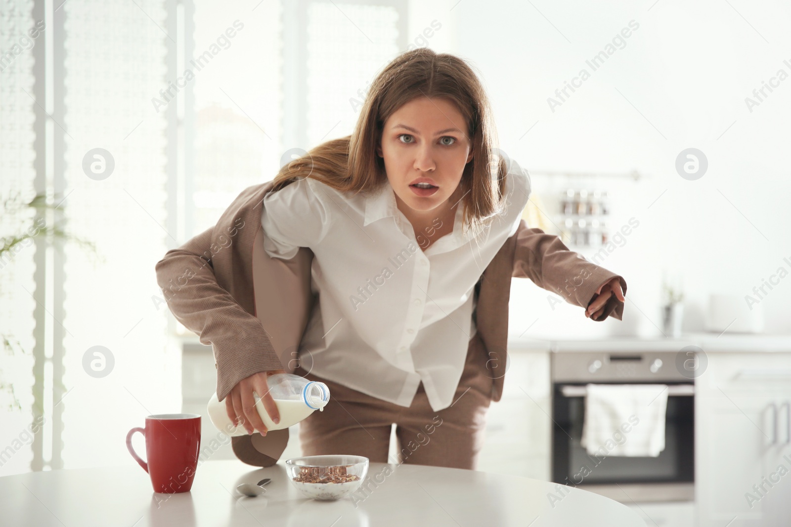 Photo of Young woman cooking breakfast in hurry at home. Morning preparations