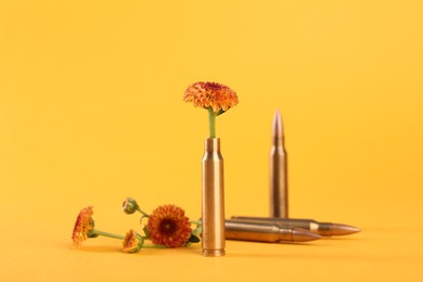 Photo of Bullets and beautiful chrysanthemum flowers on yellow background