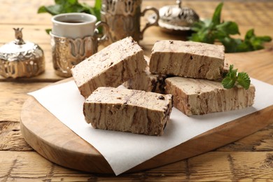 Photo of Tasty chocolate halva with mint on wooden table, closeup