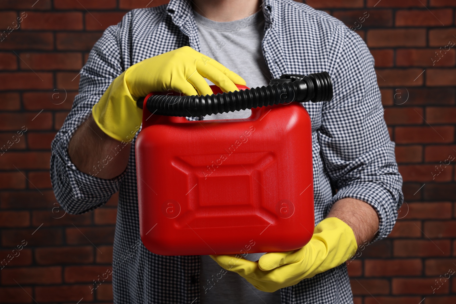 Photo of Man holding red canister against brick wall, closeup