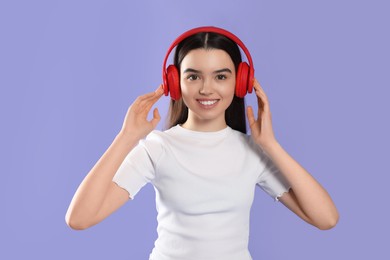 Photo of Teenage girl listening music with headphones on violet background
