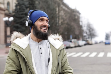 Photo of Mature man with headphones listening to music outdoors