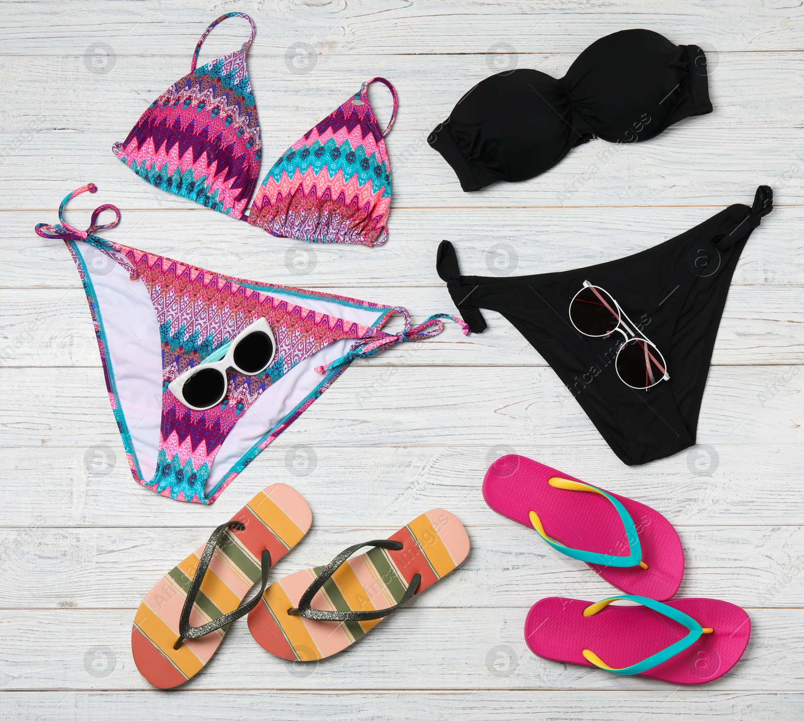 Photo of Flat lay composition with swimsuits and beach accessories on wooden background