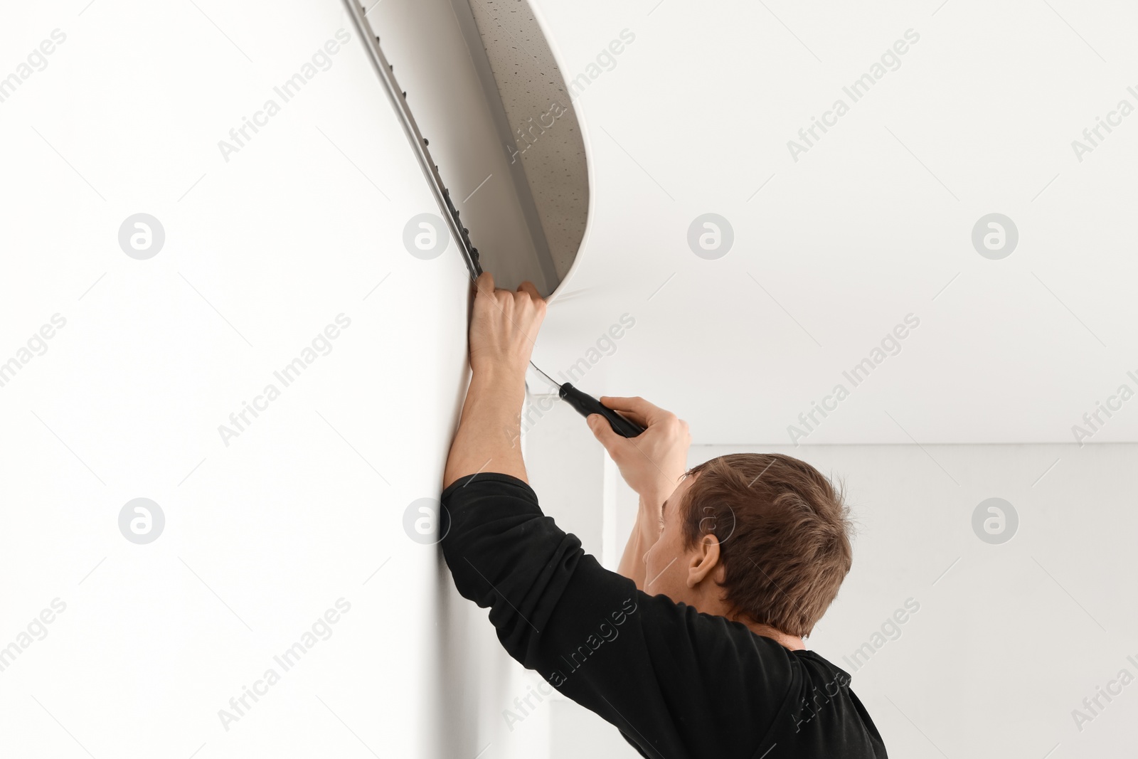 Photo of Repairman installing white stretch ceiling in room