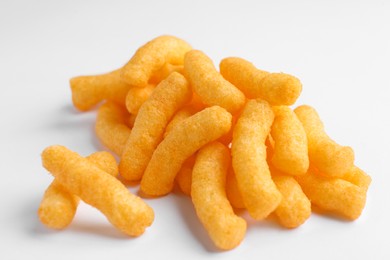 Photo of Heap of tasty cheesy corn puffs on white background, closeup