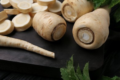 Photo of Whole and cut parsnips on wooden board, closeup