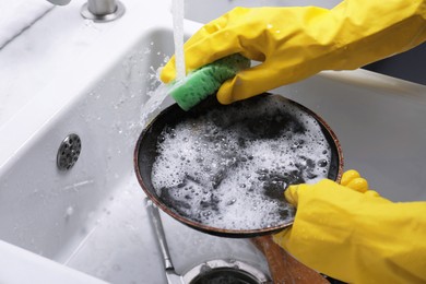 Woman washing dirty dishes in kitchen sink, closeup