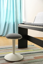 Photo of Stool and modern piano with music sheets in room