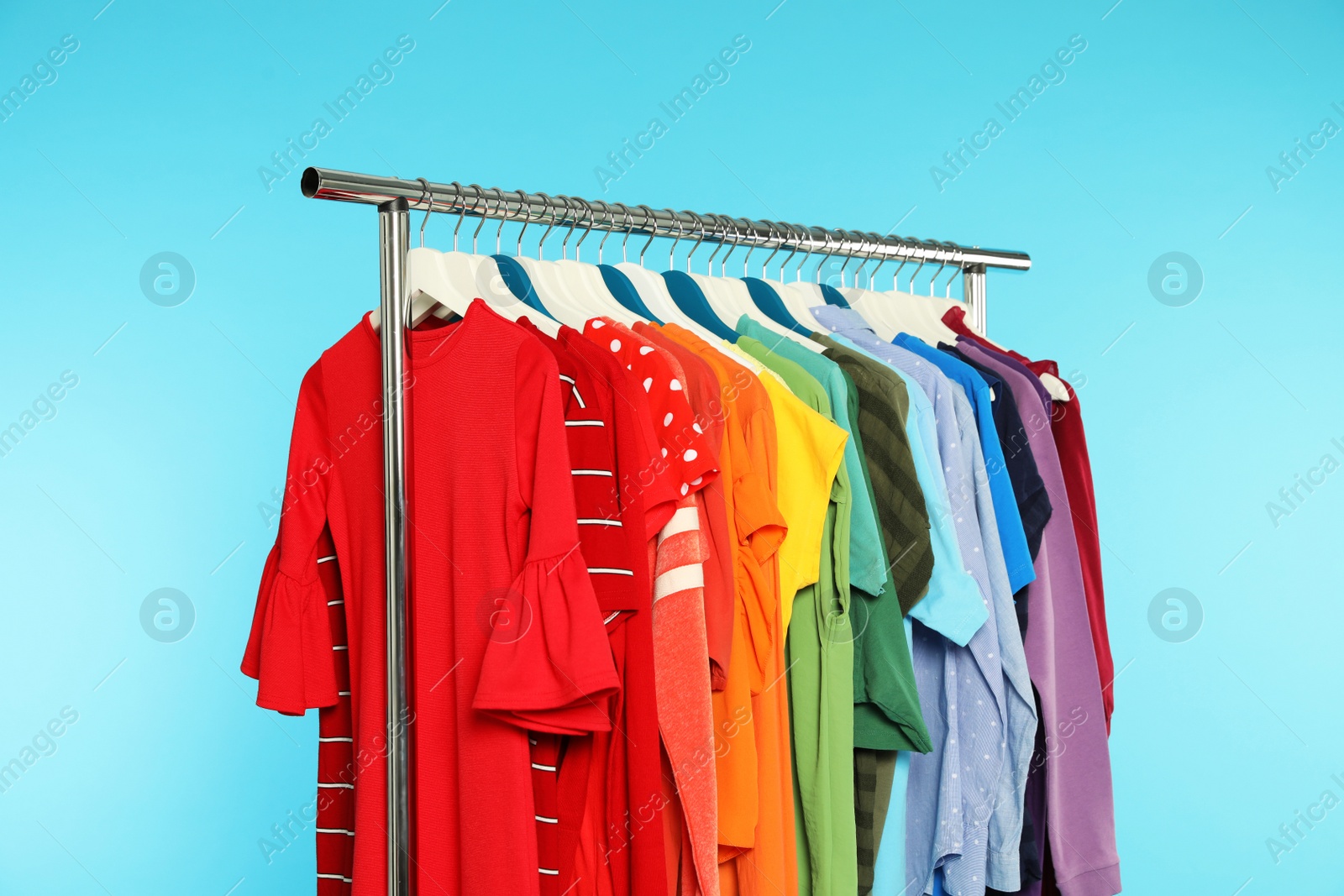 Photo of Wardrobe rack with different bright clothes on color background