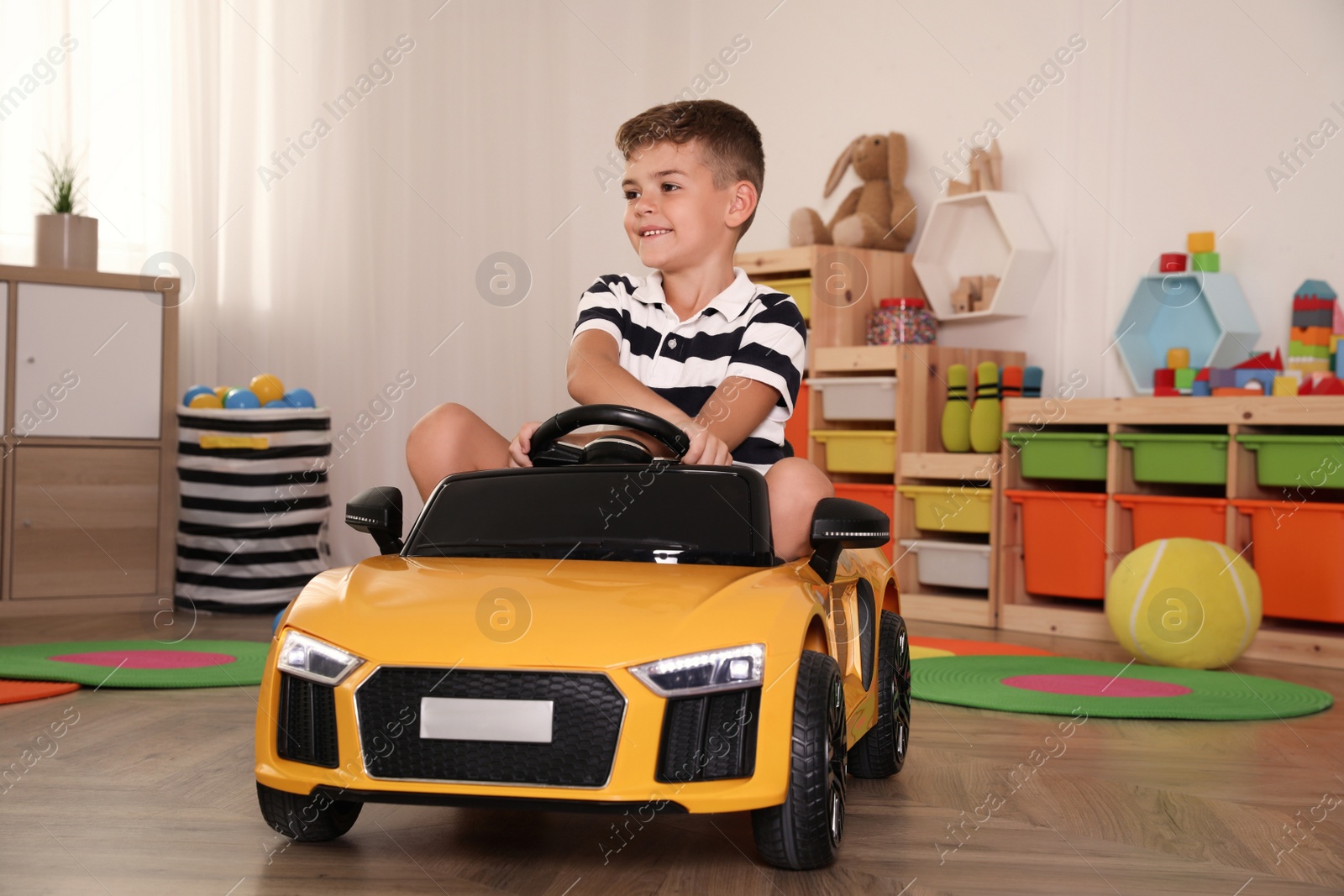 Photo of Cute little boy driving big toy car at home