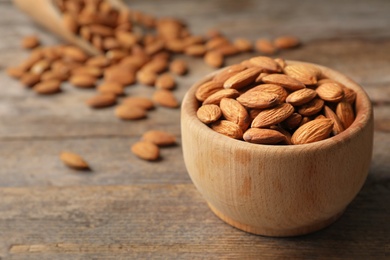 Photo of Tasty organic almond nuts in bowl on table. Space for text