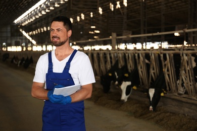 Photo of Worker with notes in cowshed on farm, space for text. Animal husbandry