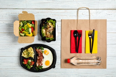 Photo of Lunchboxes with different meals on white wooden table, flat lay. Healthy food delivery