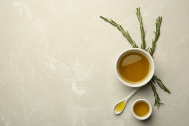 Different bowls with rosemary oil on light background, top view