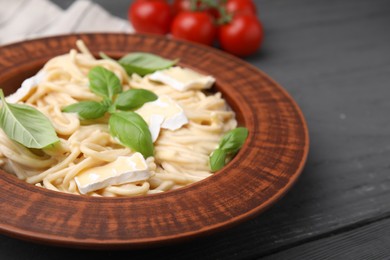 Photo of Delicious pasta with brie cheese and basil leaves on grey wooden table, closeup. Space for text