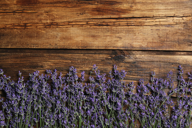 Beautiful lavender flowers on wooden background, flat lay. Space for text