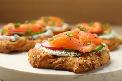 Photo of Tasty canapes with salmon, cucumber, radish and cream cheese on table, closeup