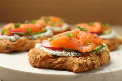 Tasty canapes with salmon, cucumber, radish and cream cheese on table, closeup