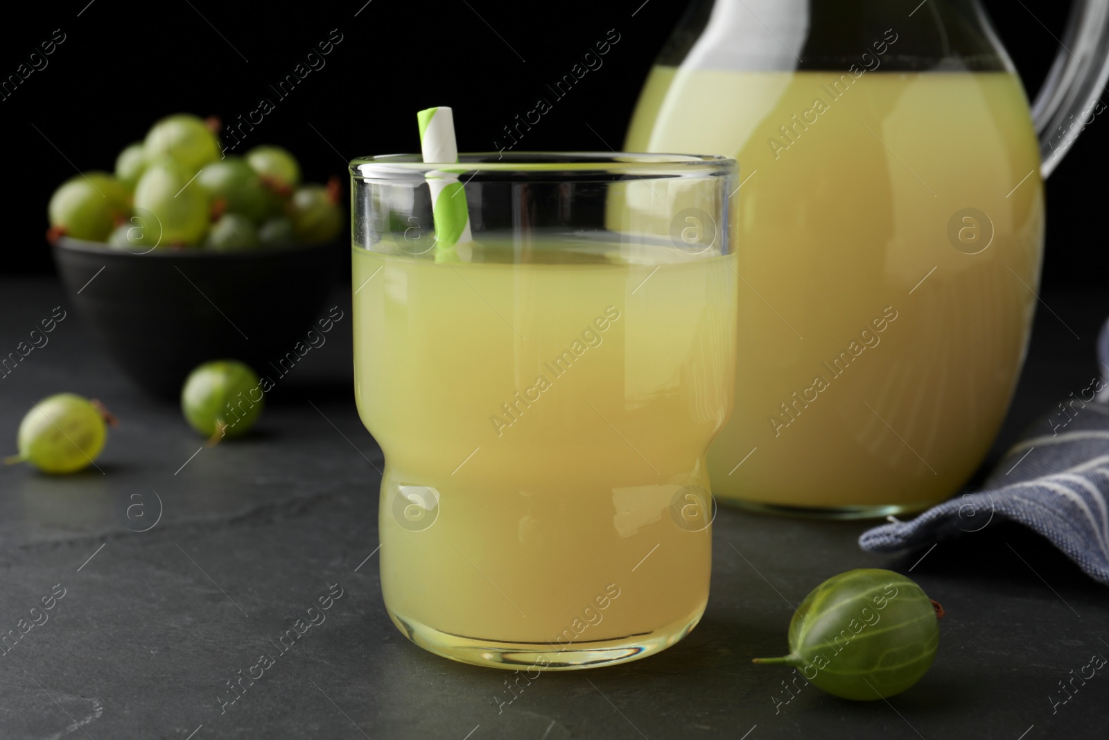 Photo of Tasty gooseberry juice in glass on black table