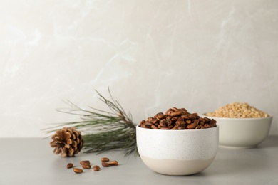 Photo of Bowl with pine nuts on table against light background. Space for text